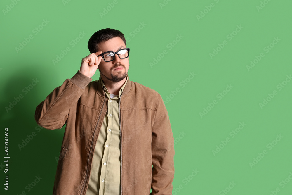 Handsome man in stylish eyeglasses on green background