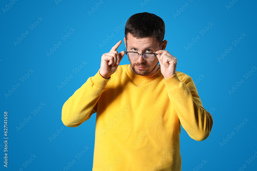 Handsome man in stylish eyeglasses on blue background