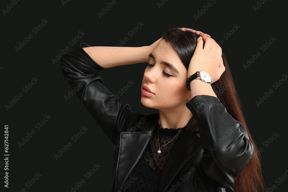 Stylish beautiful woman with wristwatch on black background