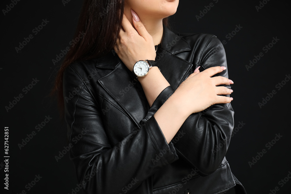 Stylish young woman with wristwatch on black background