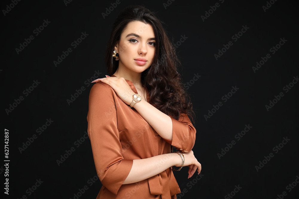 Elegant beautiful woman with wristwatch on black background