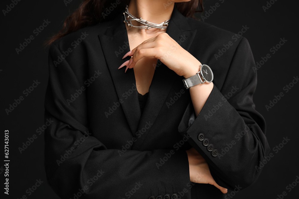 Young woman with wristwatch on black background