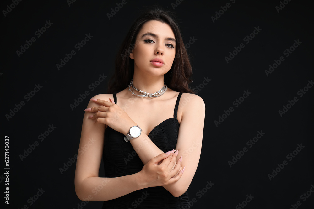 Elegant beautiful young woman with wristwatch on black background