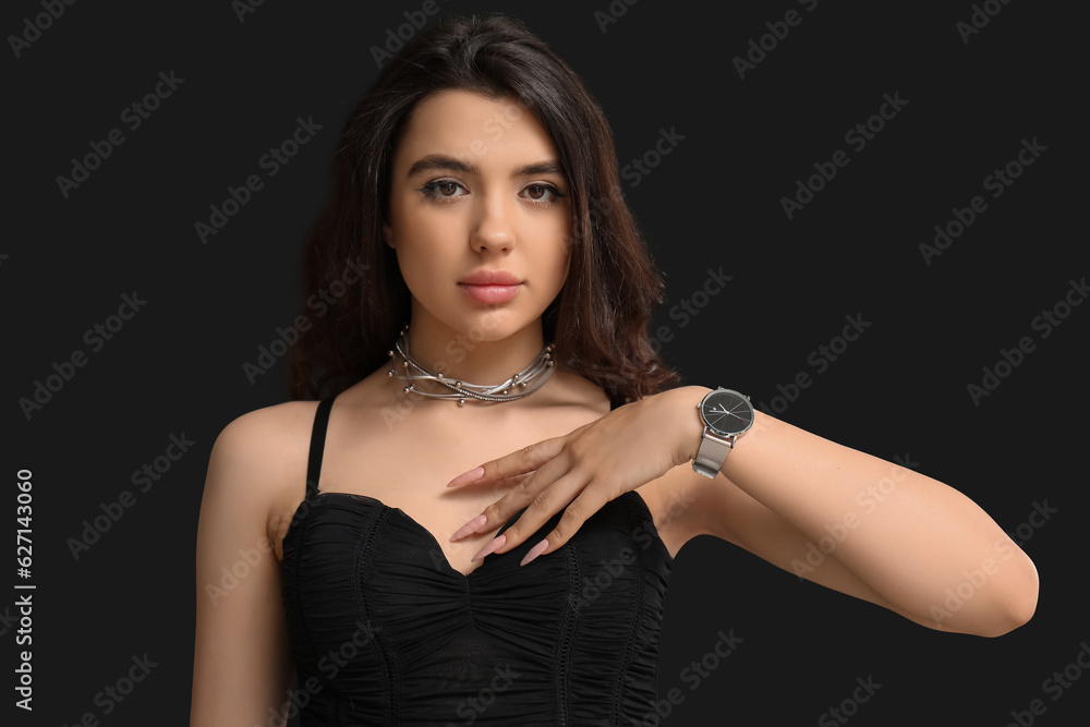 Elegant beautiful young woman with wristwatch on black background