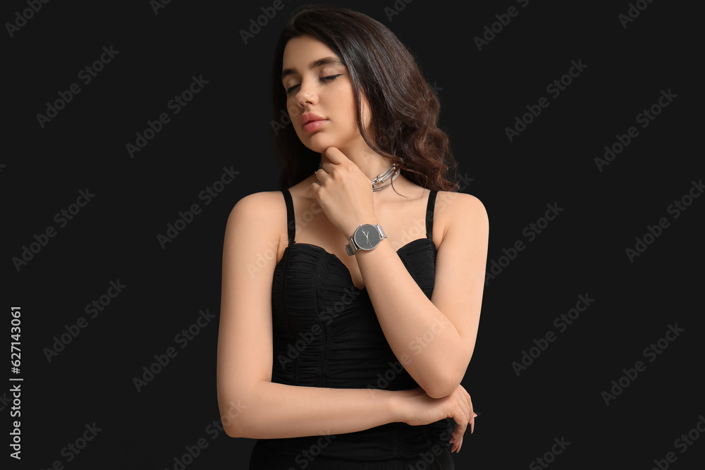 Elegant beautiful young woman with wristwatch on black background