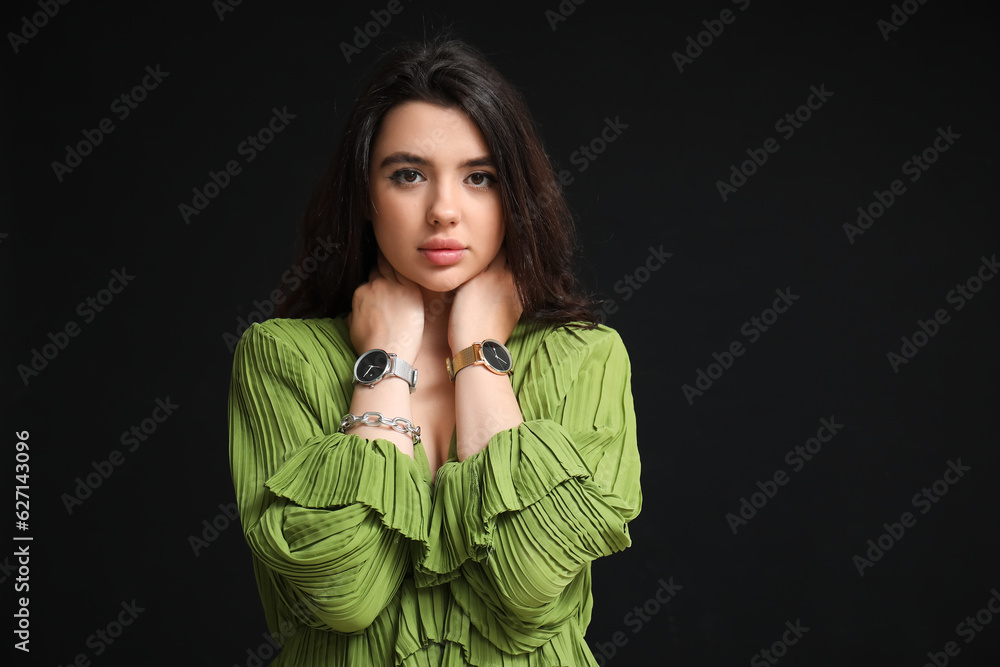 Beautiful young woman with wristwatches on black background