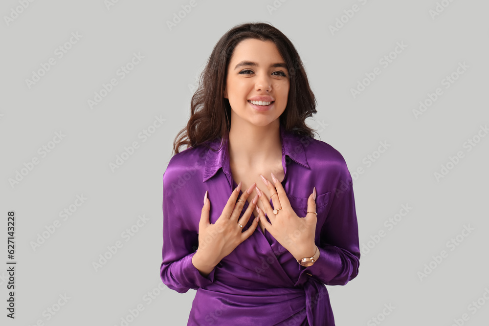 Elegant beautiful young woman with wristwatch on grey background