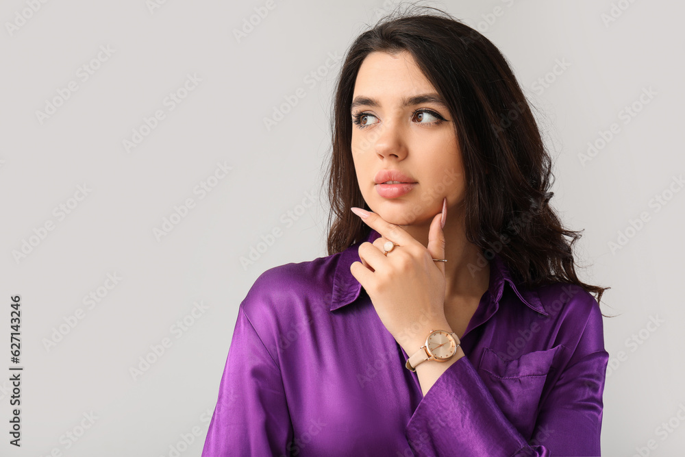 Elegant beautiful young woman with wristwatch on grey background