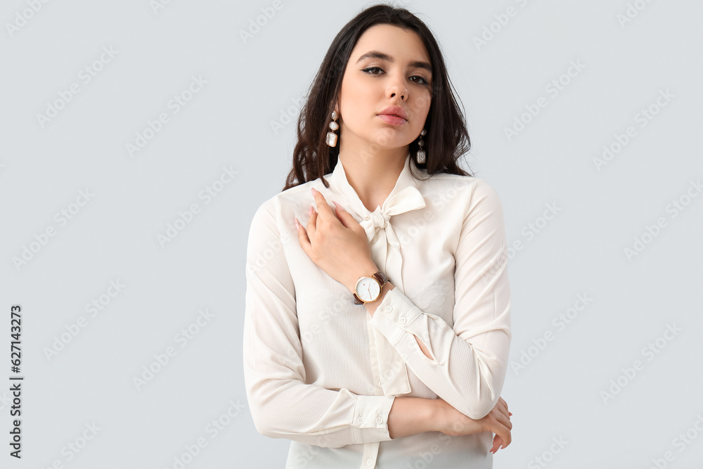 Elegant beautiful young woman with wristwatch on grey background