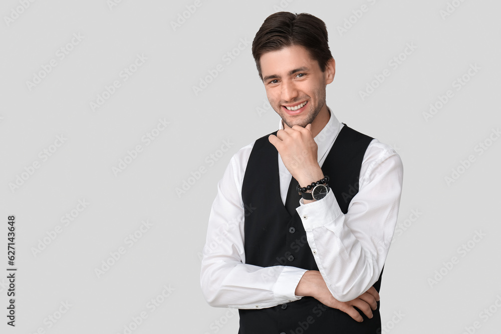 Handsome happy businessman with wristwatch on grey background