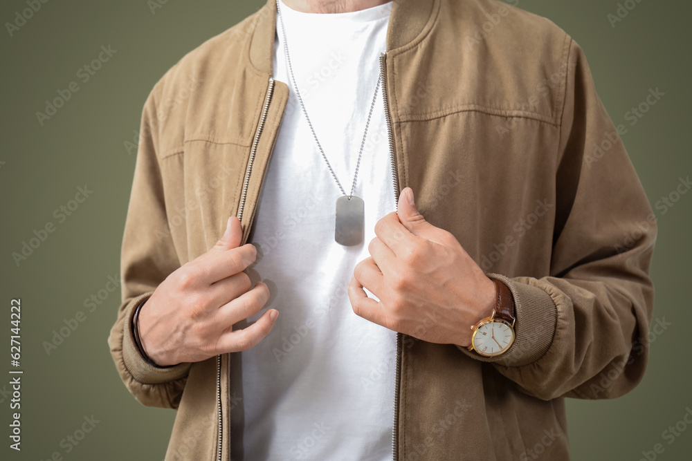 Young man with wristwatch in stylish jacket on olive background, closeup