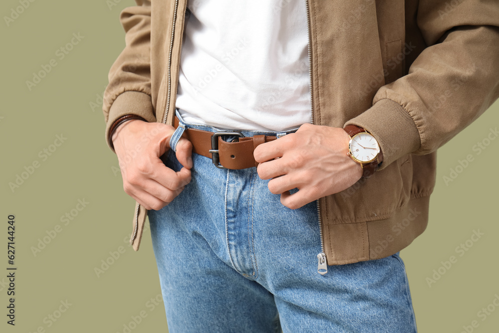 Young man with wristwatch in stylish jacket on olive background