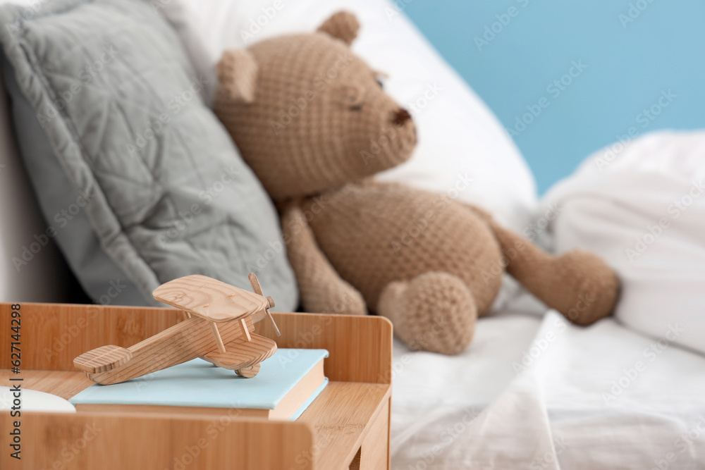 Wooden toy airplane and books on bedside table in childrens bedroom, closeup