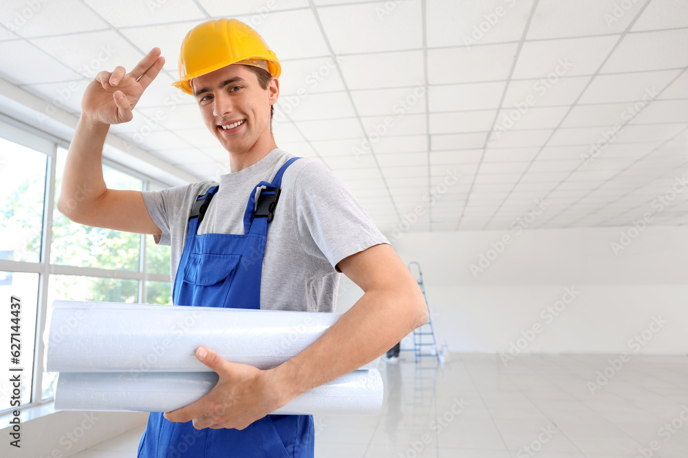 Male builder with wallpapers saluting in room