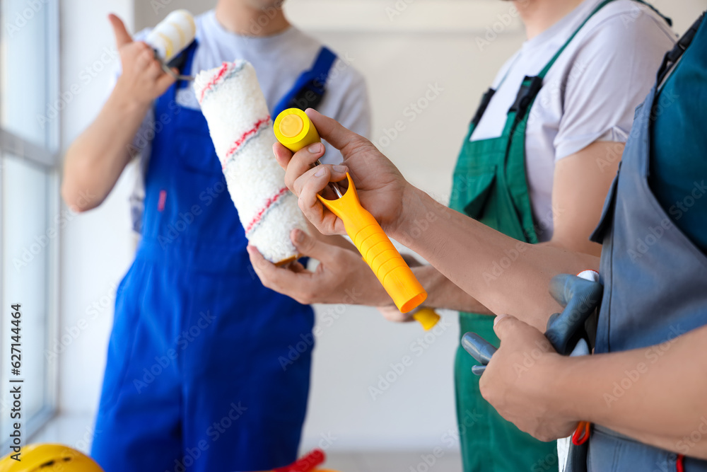 Team of male builders with paint rollers working in room, closeup