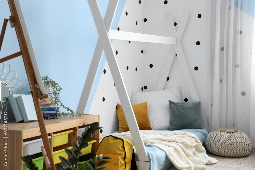 Interior of childrens bedroom with cozy bed, easel and pouf