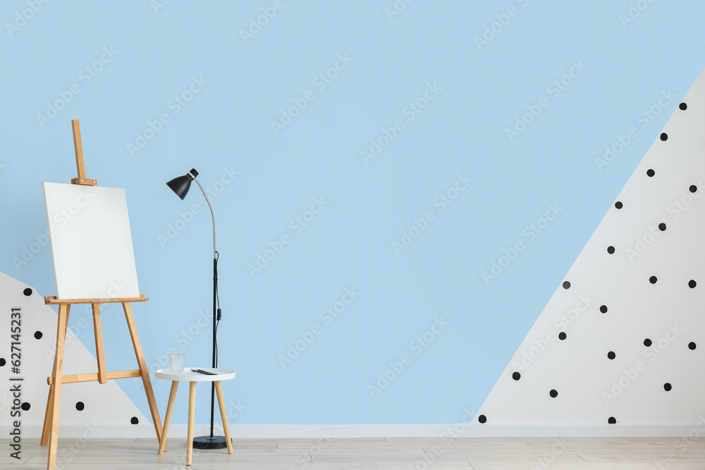 Lamp and easel near blue wall