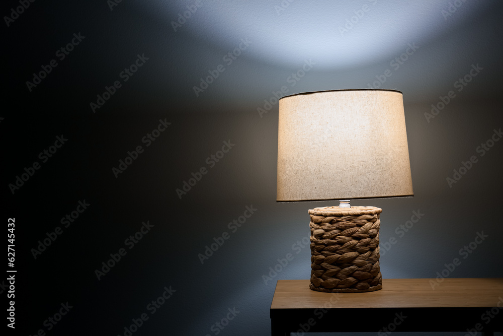 Glowing lamp on wooden table in dark room