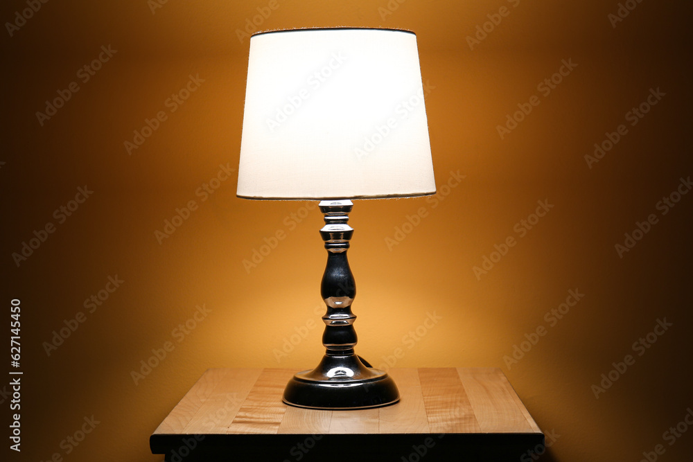 Glowing lamp on wooden table in dark room