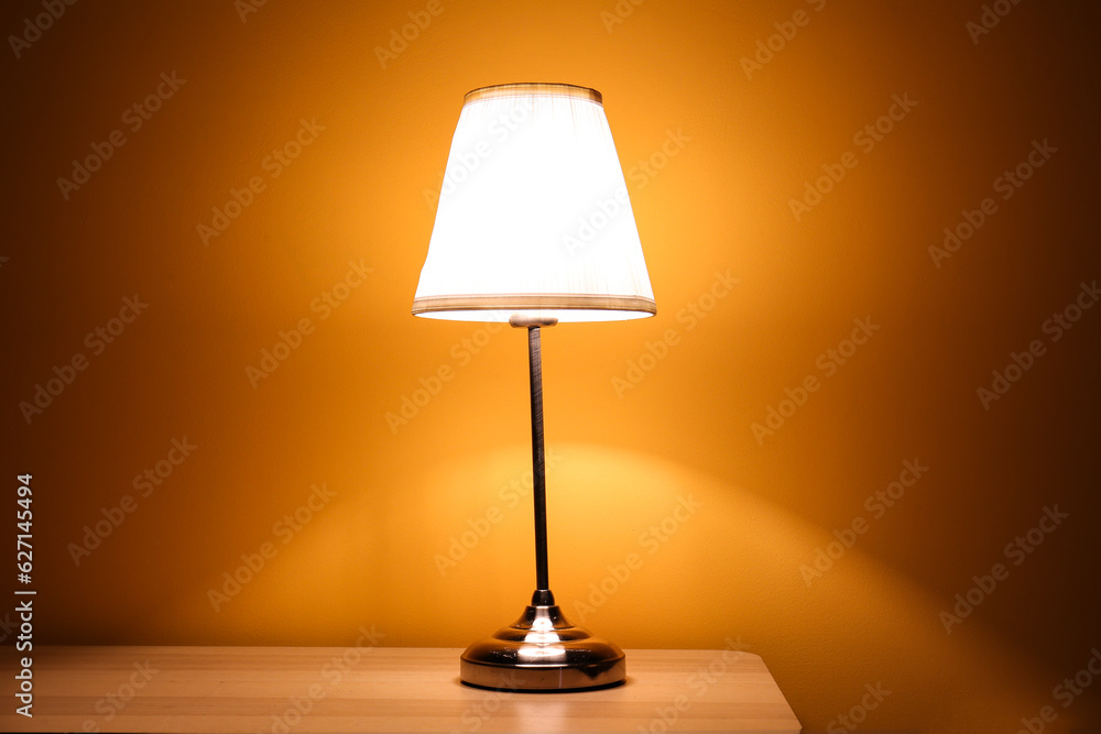 Glowing lamp on wooden table in dark room