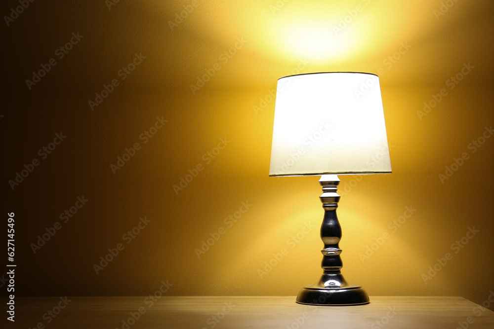 Glowing lamp on wooden table in dark room