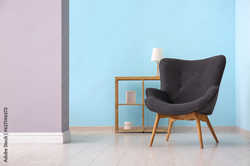 Grey armchair and shelving unit near blue wall