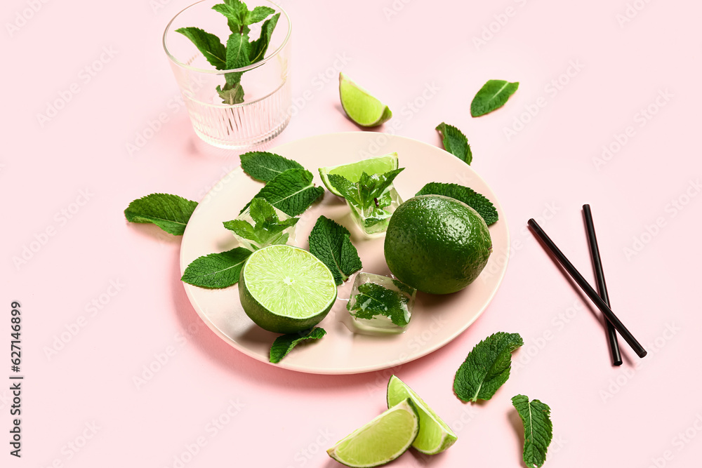 Composition with fresh mint leaves, limes and ice cubes on pink background