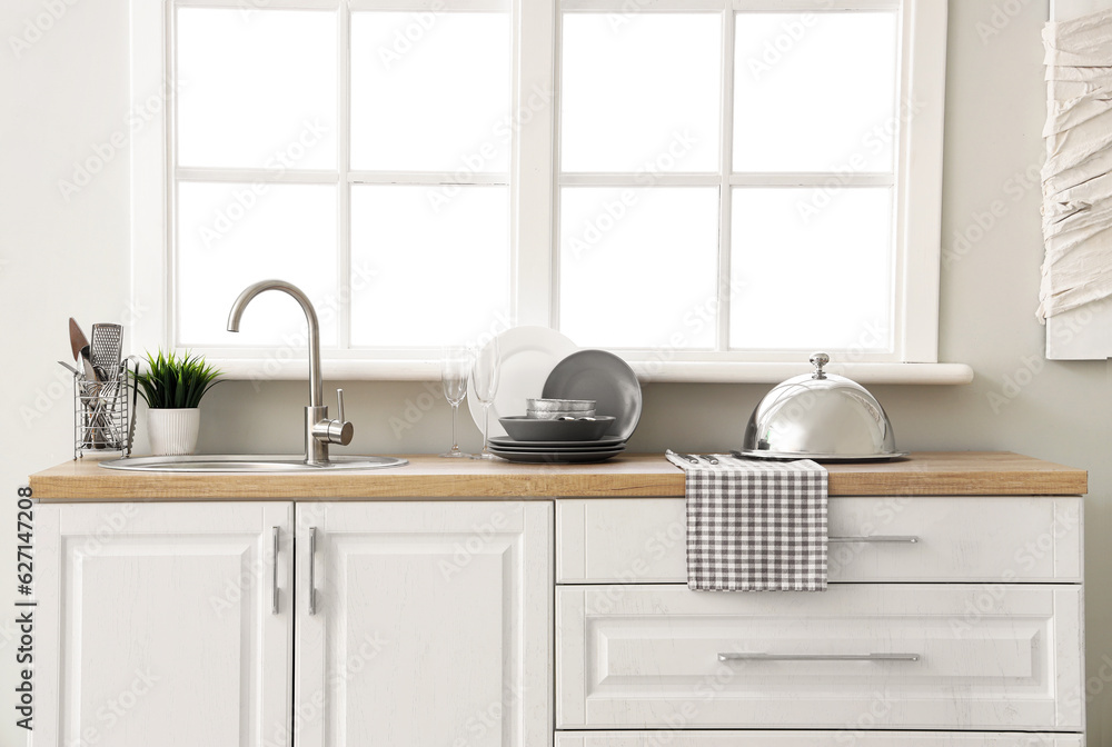 Kitchen counter with sink, clean dishes and cloche near window