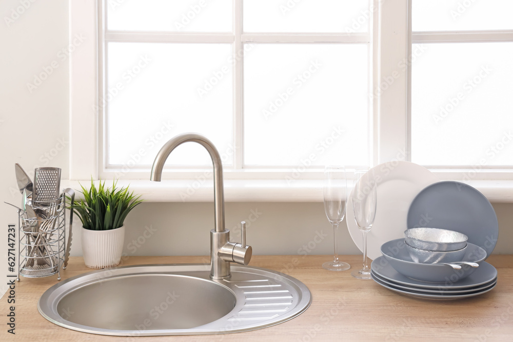 Kitchen counter with sink and clean dishes near window