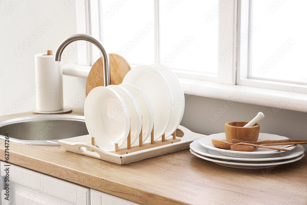 Kitchen counter with sink, plate rack and clean dishes near window