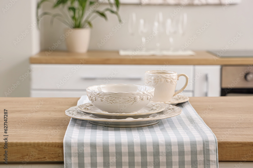 Clean plates, bowl and cup on wooden kitchen countertop, closeup