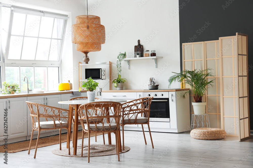 Interior of light kitchen with white counters, dining table and big window