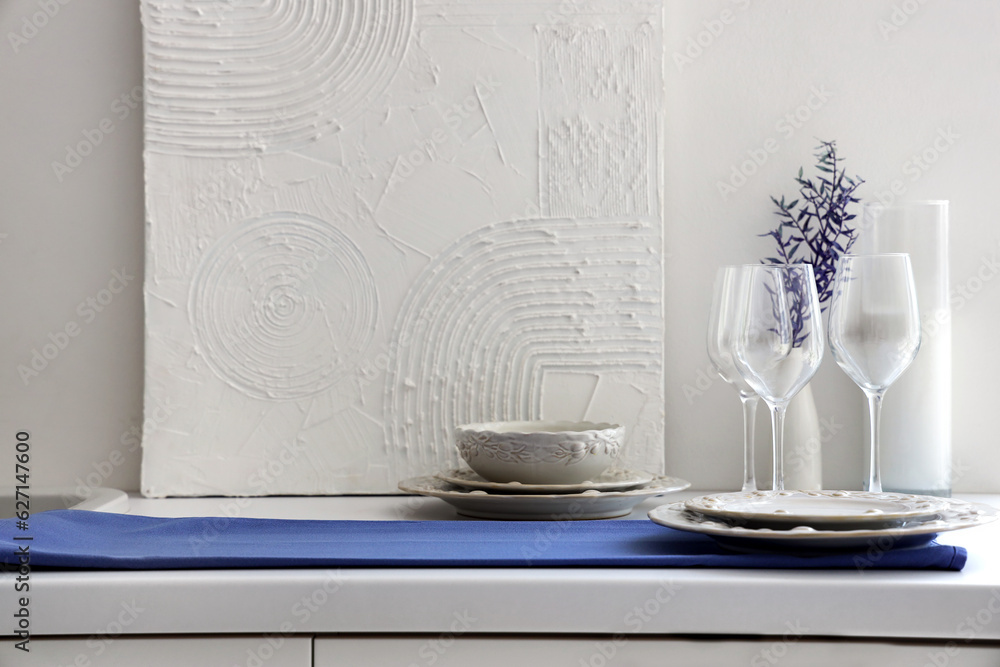 Clean glasses, plates and bowl on white kitchen counter