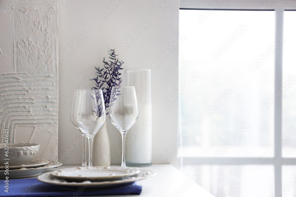 Clean glasses, plates and bowl on white kitchen counter