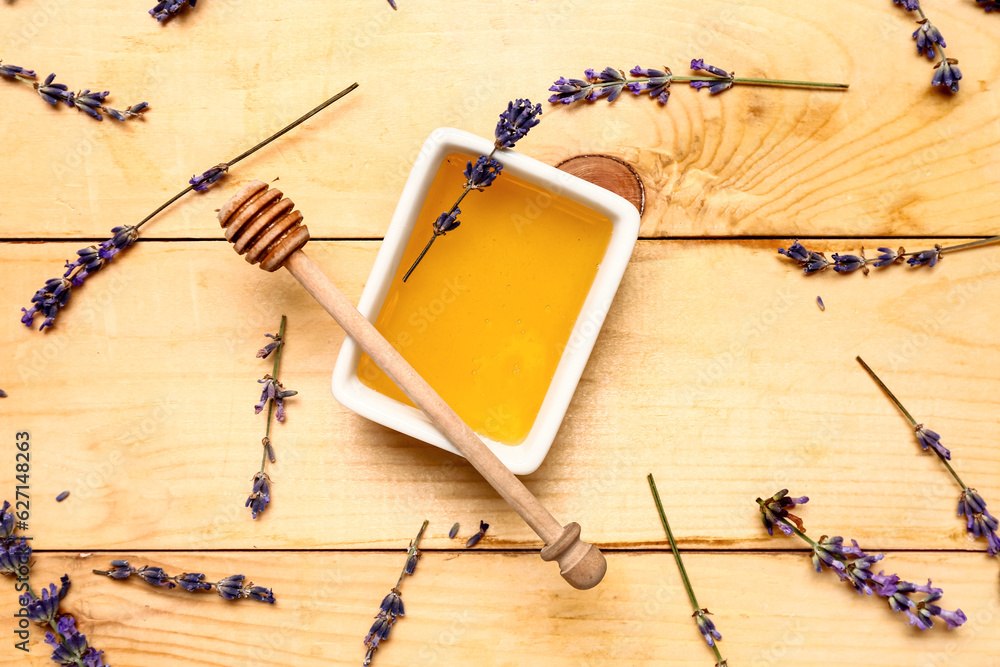 Bowl of sweet lavender honey, dipper and flowers on wooden background