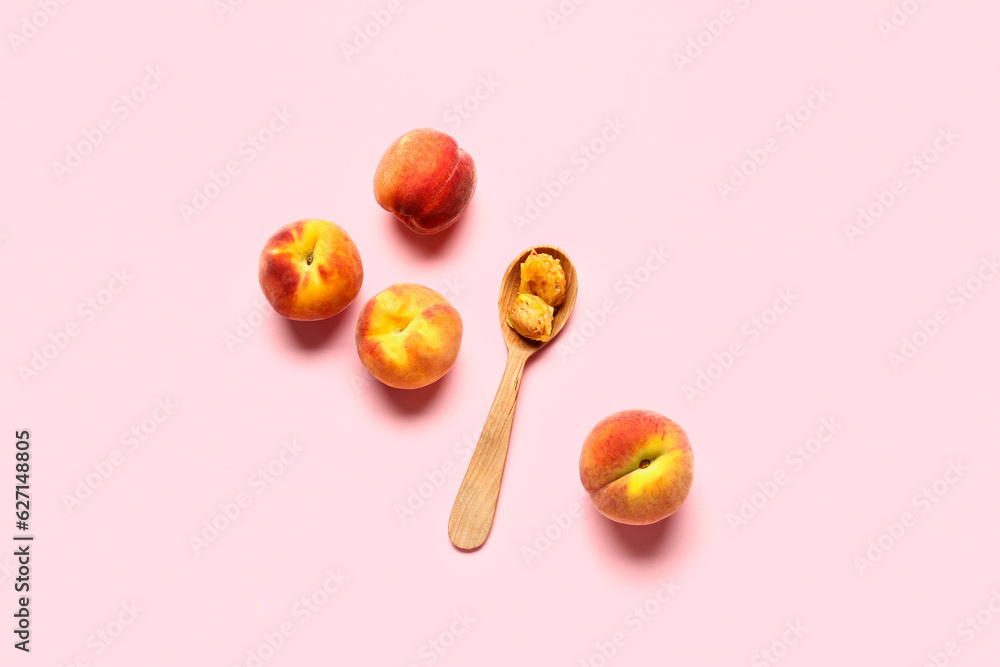 Sweet peaches and spoon on pink background