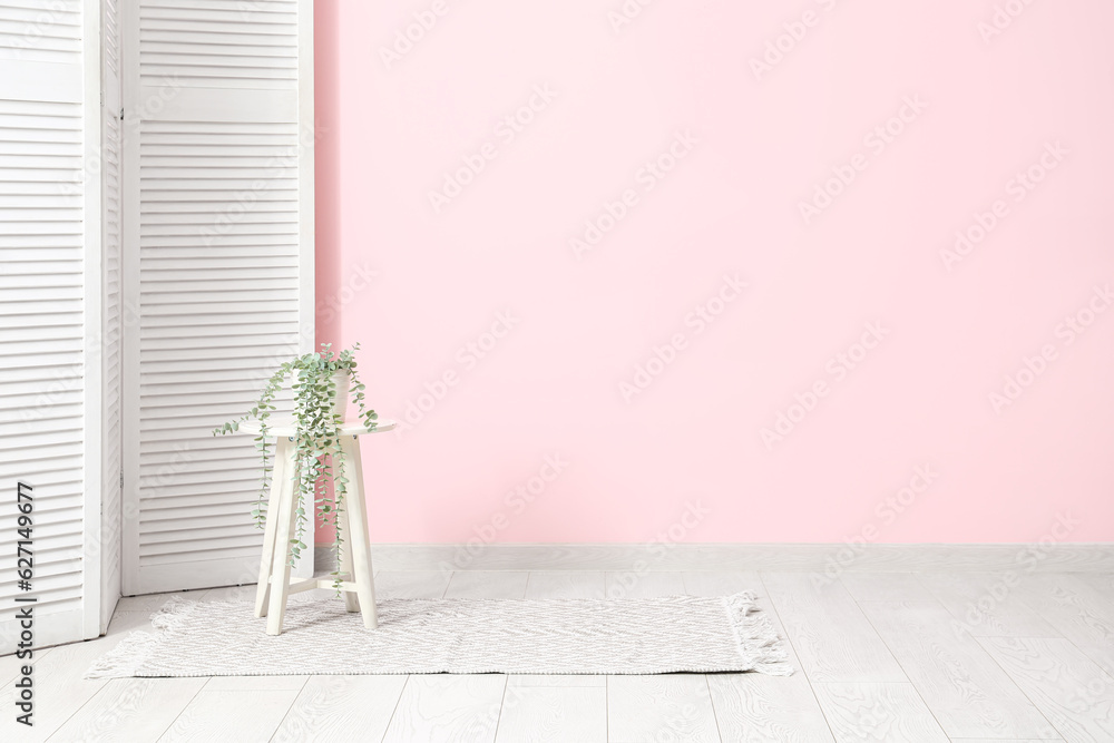 Interior of living room with houseplant on stool and stylish rug