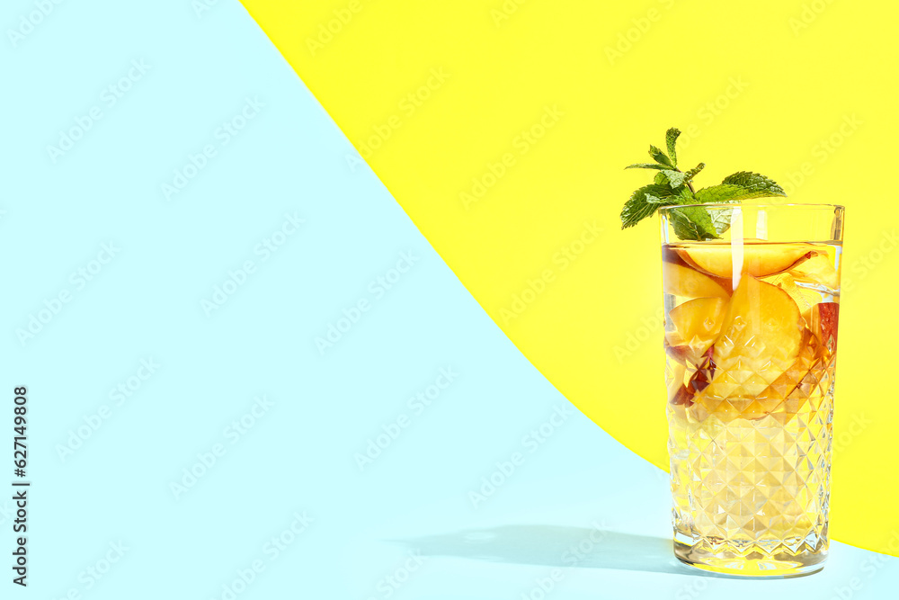 Glass of fresh peach lemonade with mint on colorful background