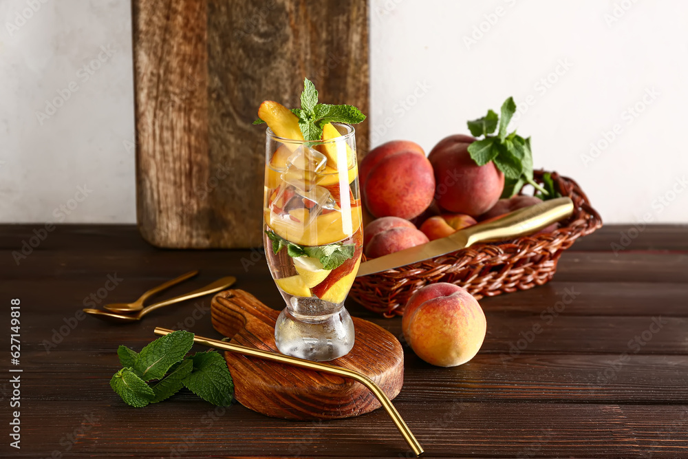 Board with glass of fresh peach lemonade and mint on wooden table