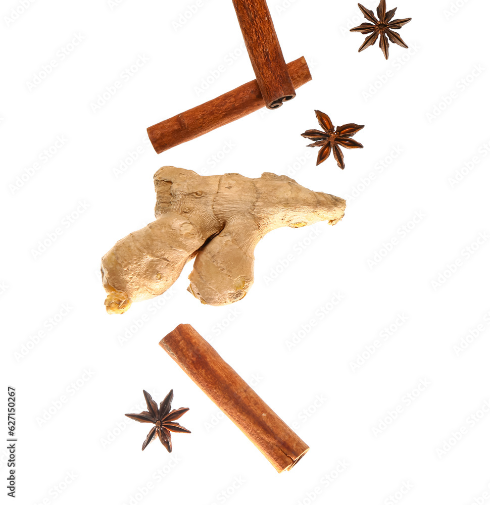 Flying cinnamon sticks, anise stars and ginger root on white background