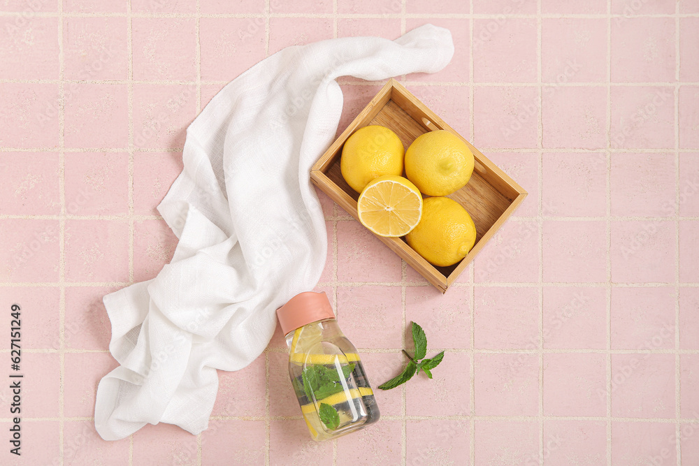 Sports bottle of infused water with lemon and blueberries on pink tile table