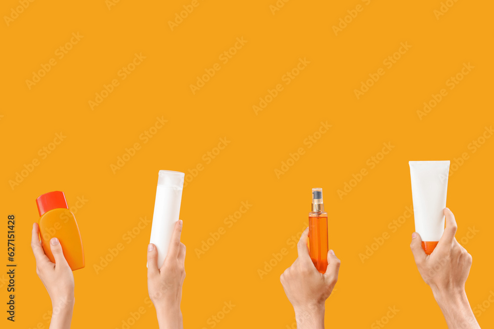 Female hands with bottles of sunscreen cream on yellow background