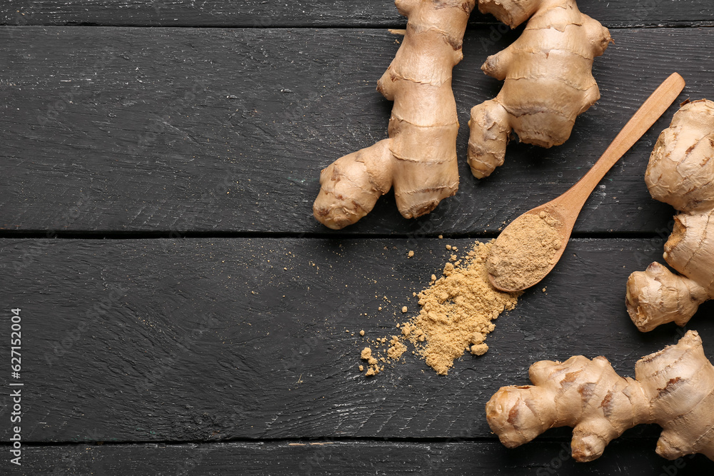 Fresh ginger roots and spoon with dried powder on black wooden background