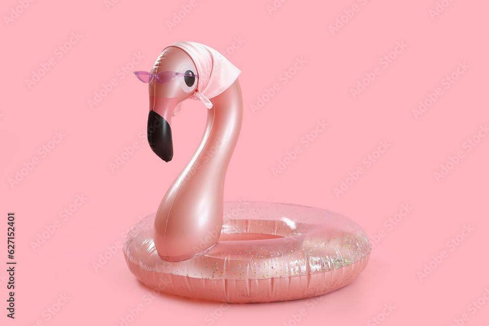 Swim ring in shape of flamingo with sunglasses and scarf on pink background