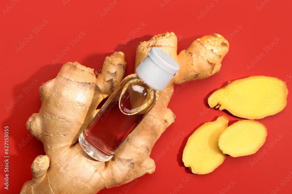 Bottle of ginger cosmetic oil on red background