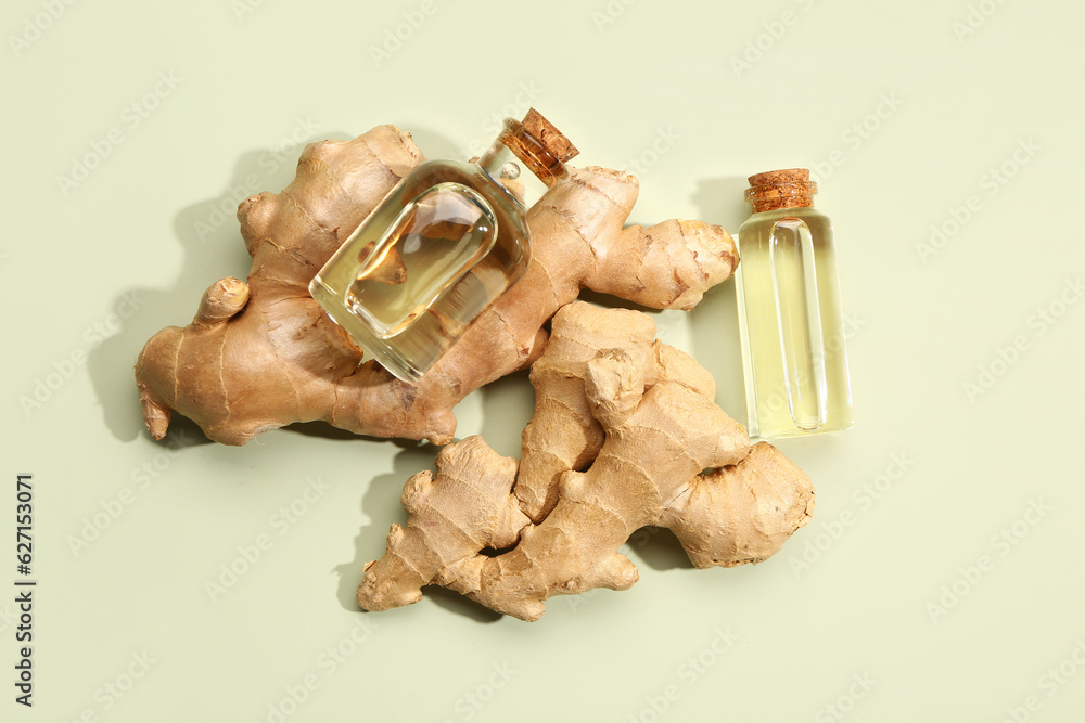 Bottles of ginger cosmetic oil on green background