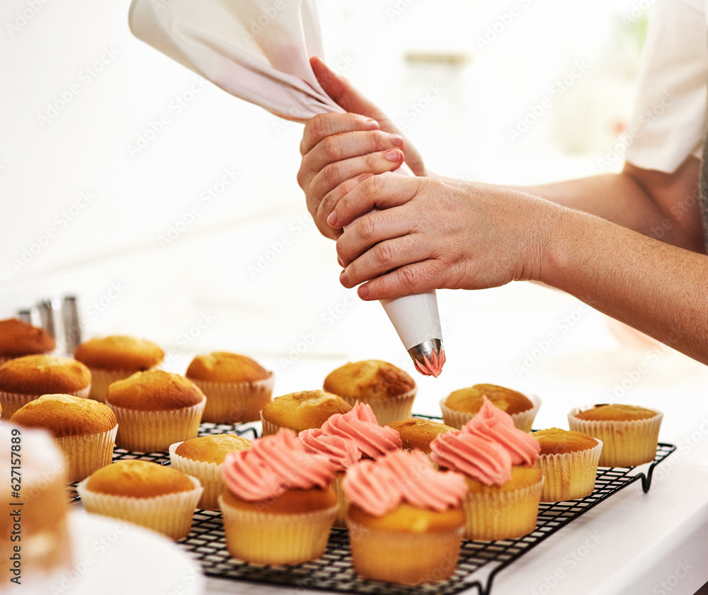 Add a little magic. Cropped shot of an unrecognizable woman piping icing onto her cupcakes.