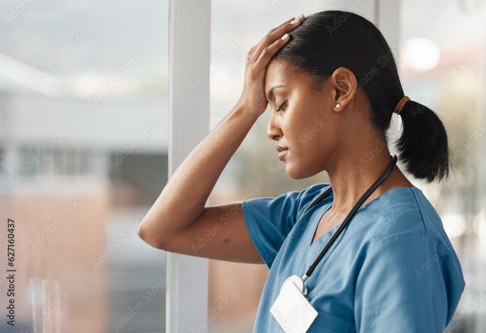 Mental health, doctor with headache and stress standing at window at hospital. Burnout or overworked