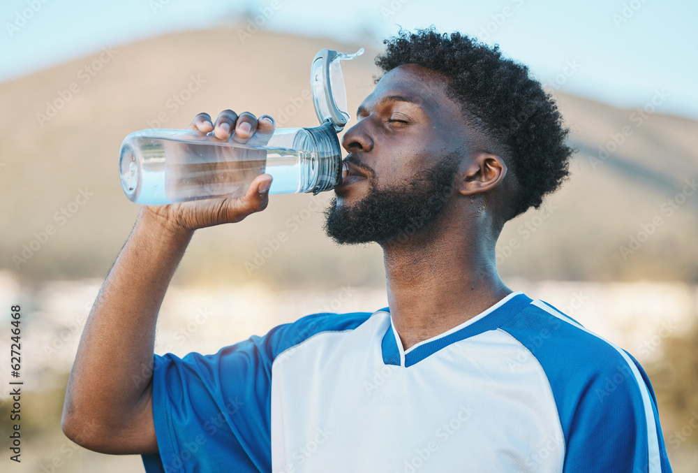 Black man, fitness or soccer player drinking water in training, exercise or workout in football fiel