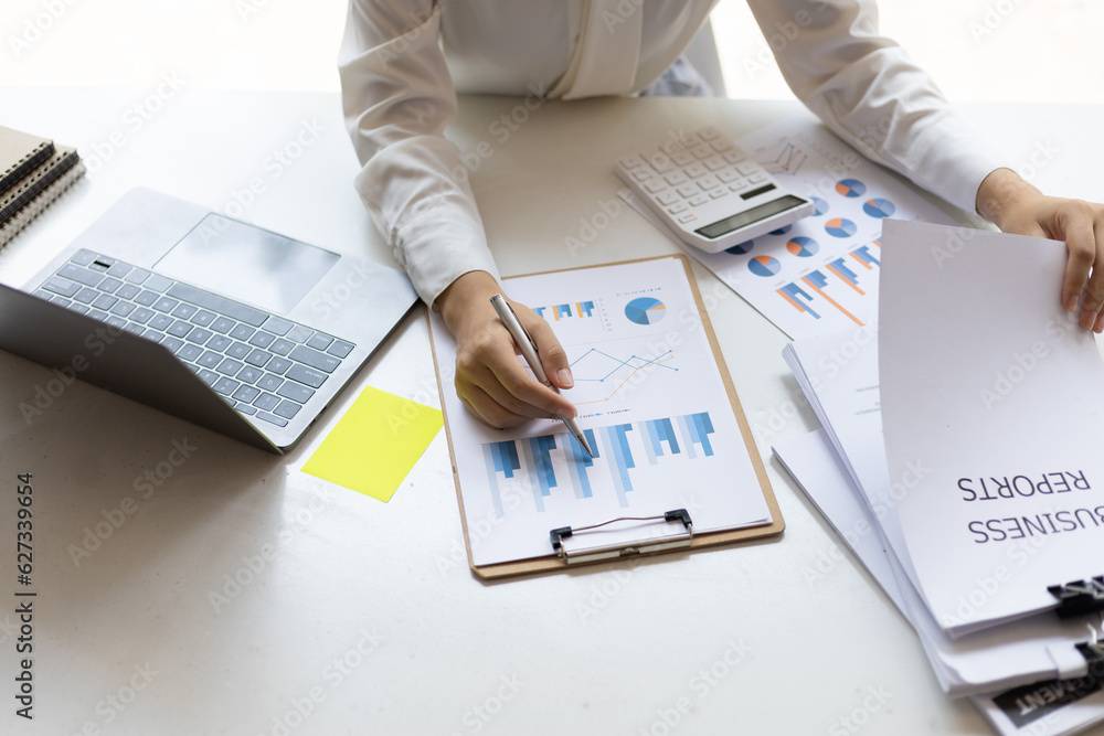 Business woman working on paperwork in the office, analysis of financial charts in business reports.